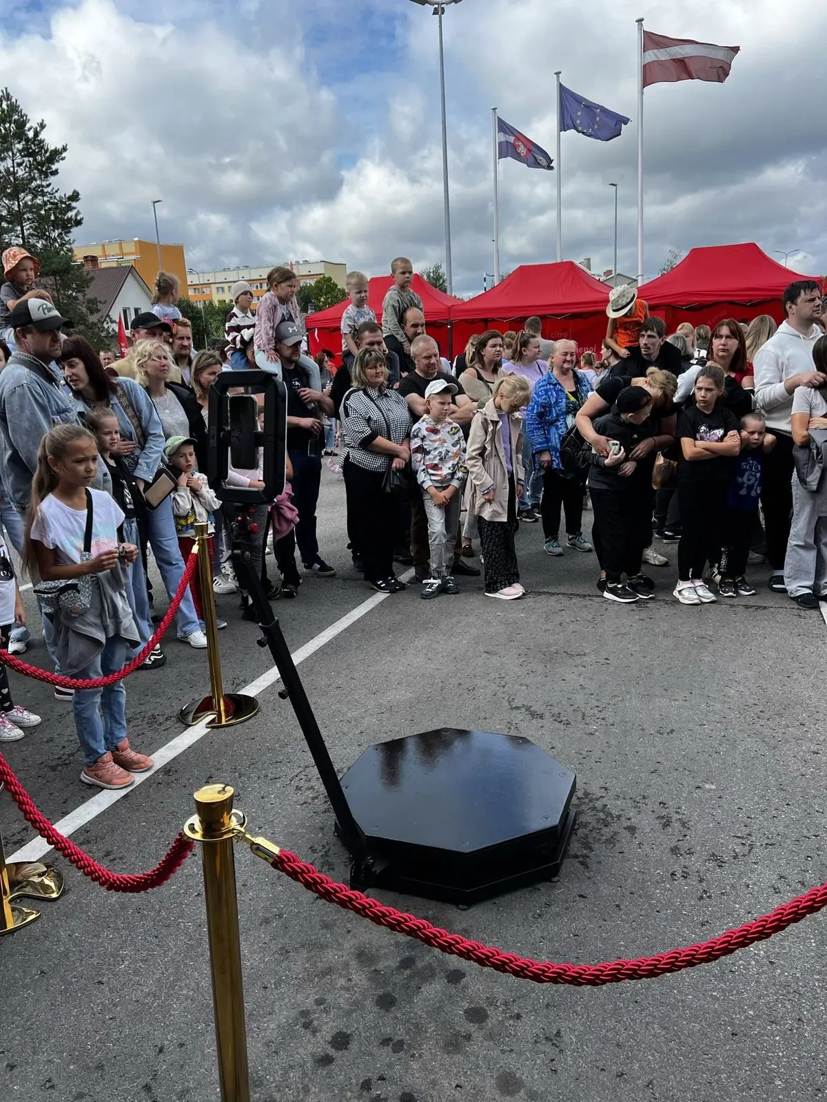 360 video spineris ar sarkanām norobežojuma lentēm laukumā, apkārt svētku apmeklētāji