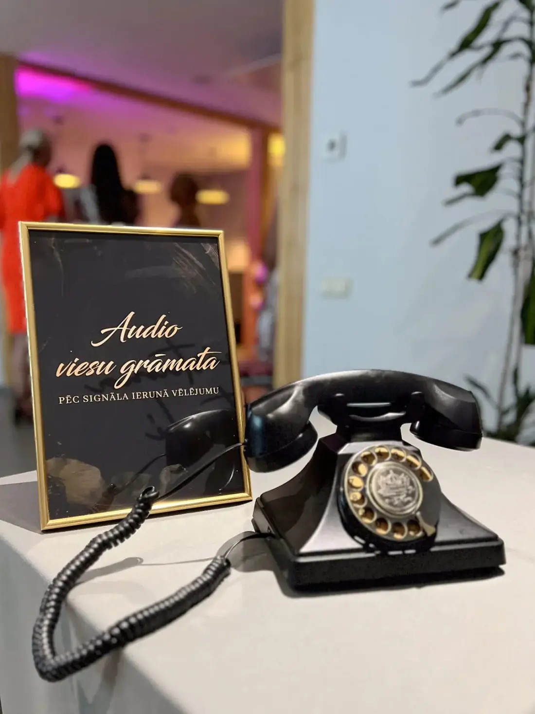 Melns retro telefons uz galda ar zelta rāmīti “Audio viesu grāmata”